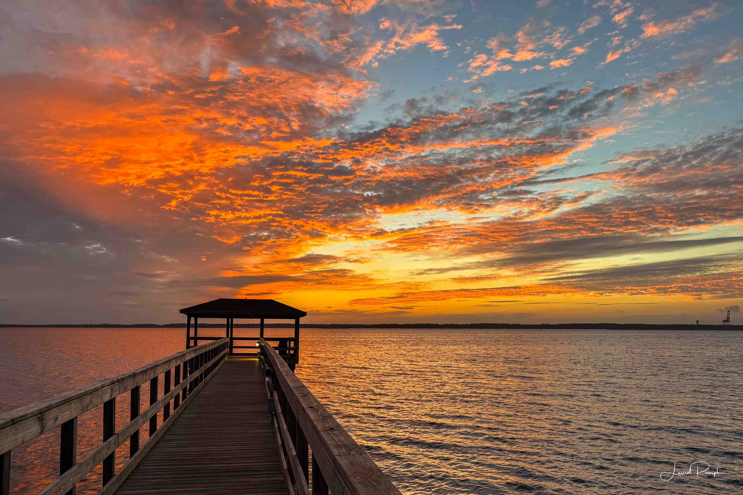 Orange and blue sunset sky over the Cape Fear River and the Fort Fisher Pier in North Carolina.