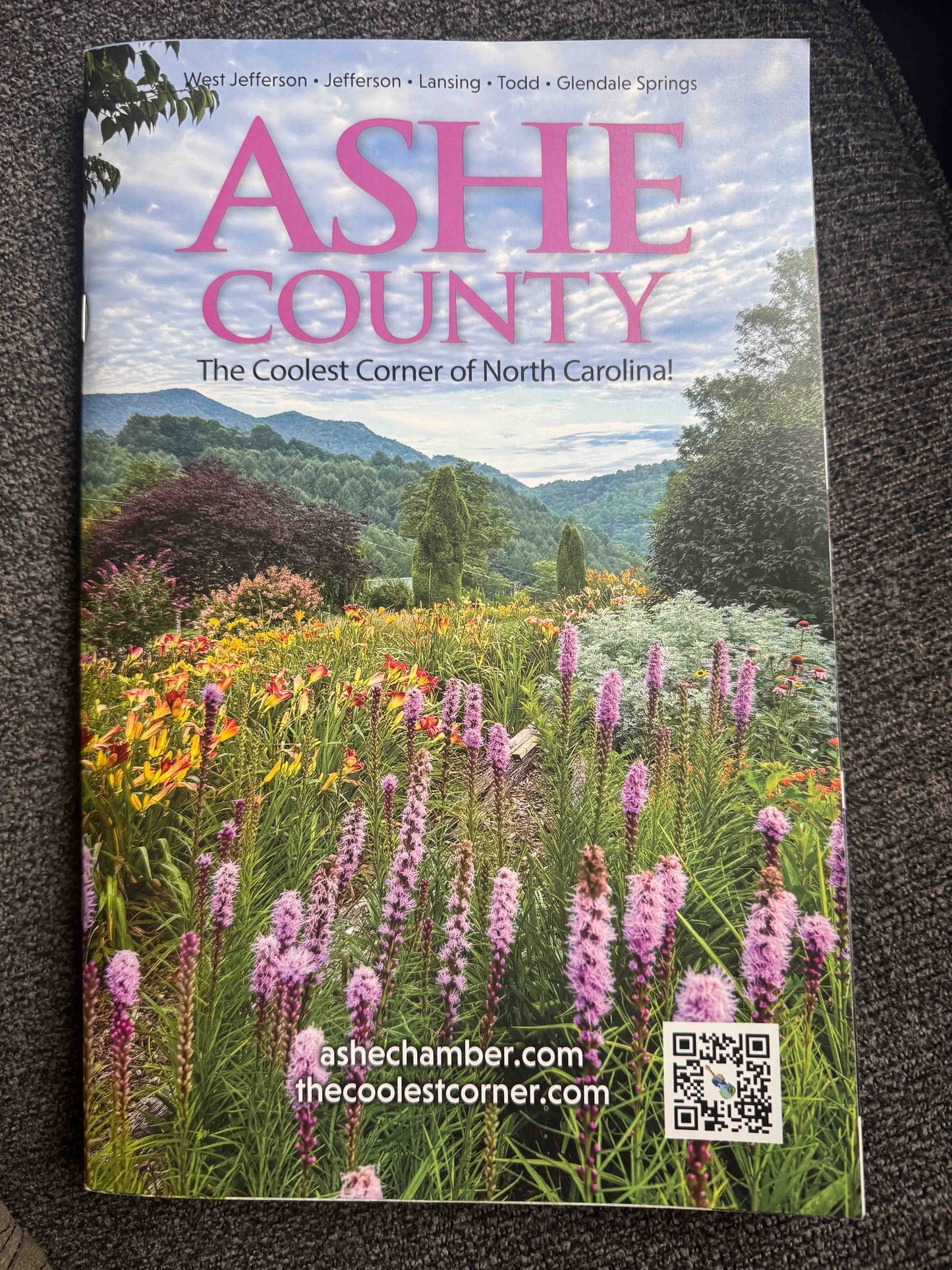 Ashe County Visitor's Guide cover featuring a scenic view of a flower field with mountains and text about Ashe County, North Carolina.