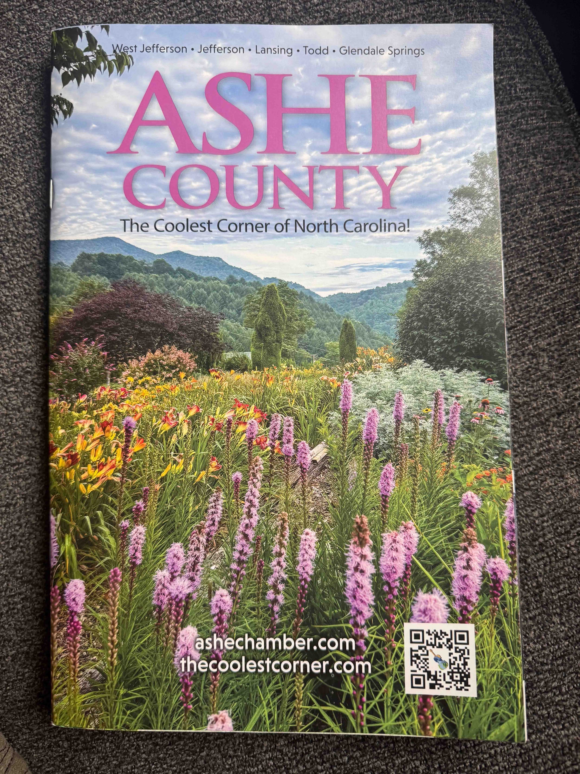 Ashe County Visitor's Guide cover featuring a scenic view of a flower field with mountains and text about Ashe County, North Carolina.