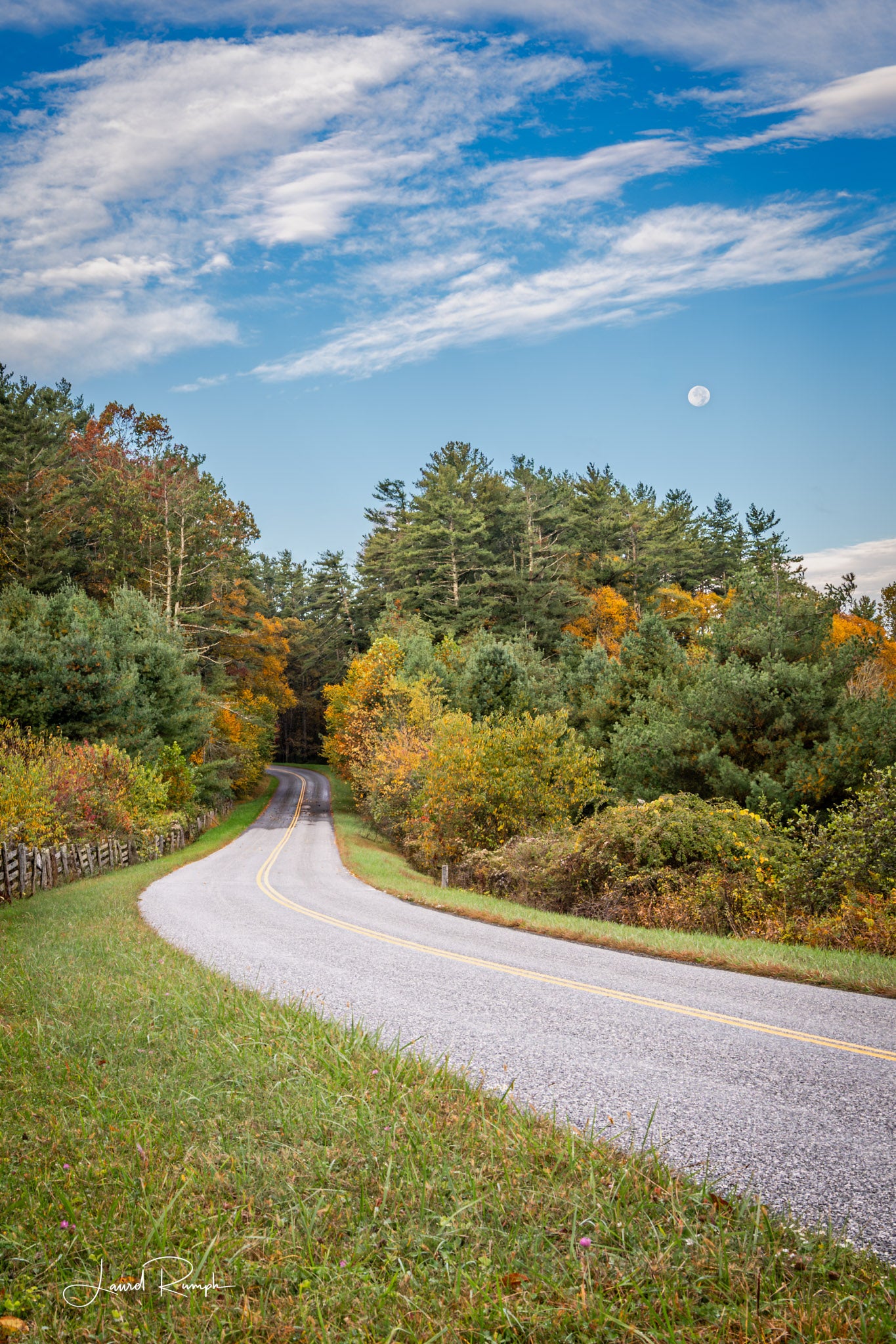 Blue Ridge Parkway winding through a forest with autumn foliage and a clear blue sky with a Moon overlooking... Ashe County, North Carolina. 2x3 crop