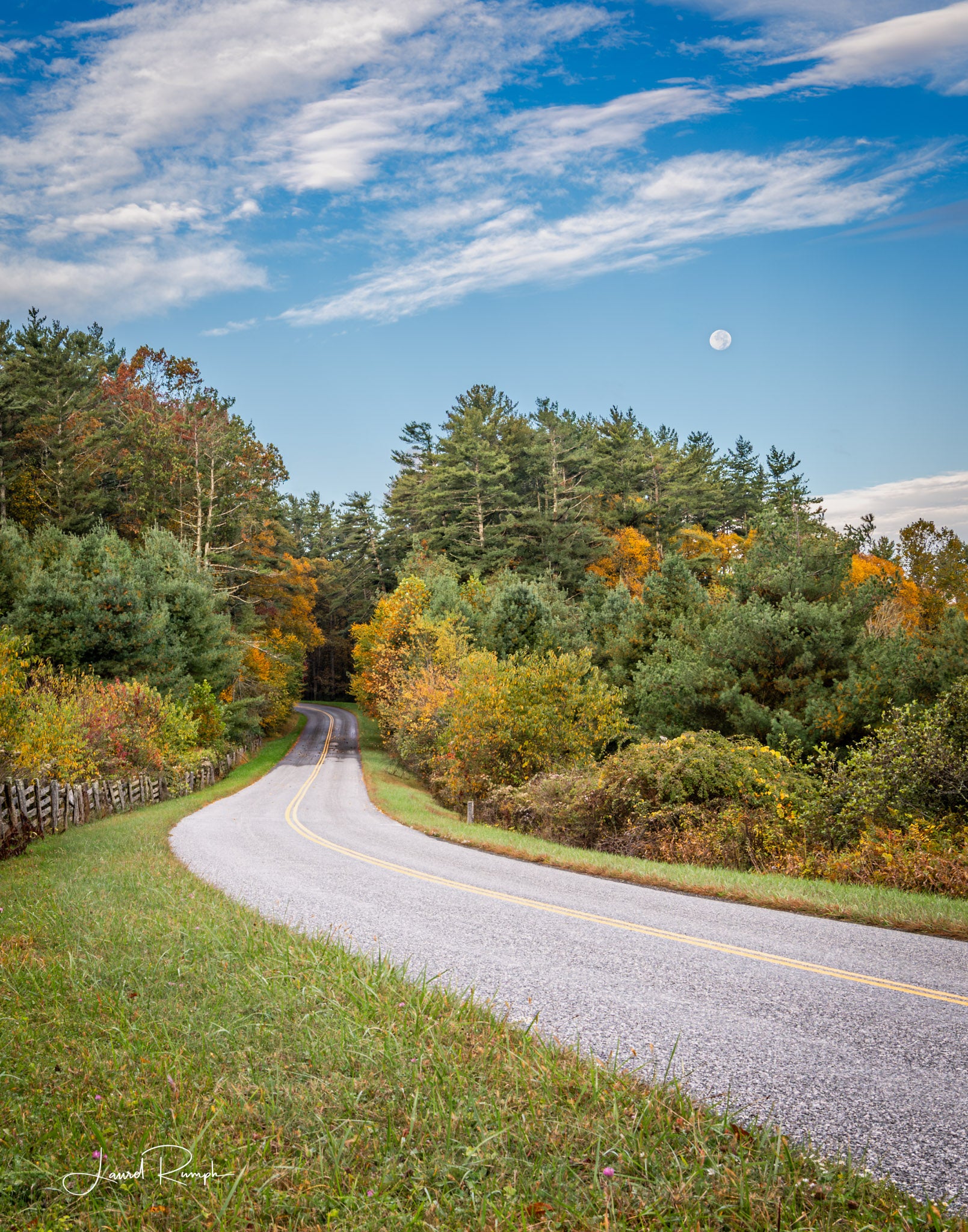 Blue Ridge Parkway winding through a forest with autumn foliage and a clear blue sky with a Moon overlooking... Ashe County, North Carolina. 4x5 crop