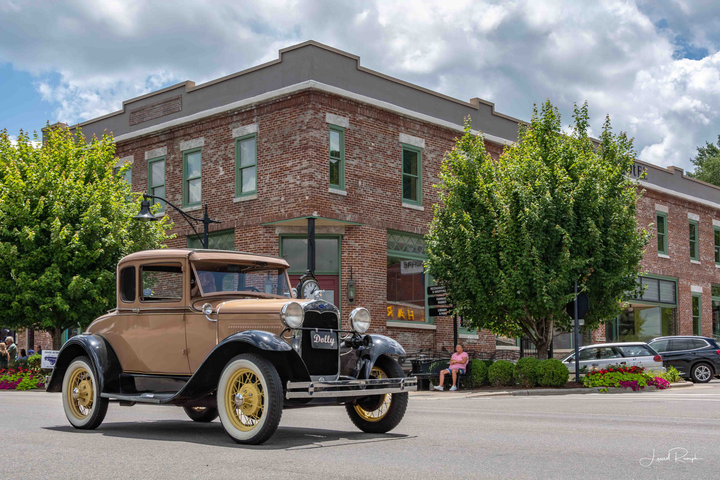Vintage Model A (named Dolly) driving past the Old Hotel in West Jefferson, North Carolina during a Cruise-In event under a clear blue sky.
