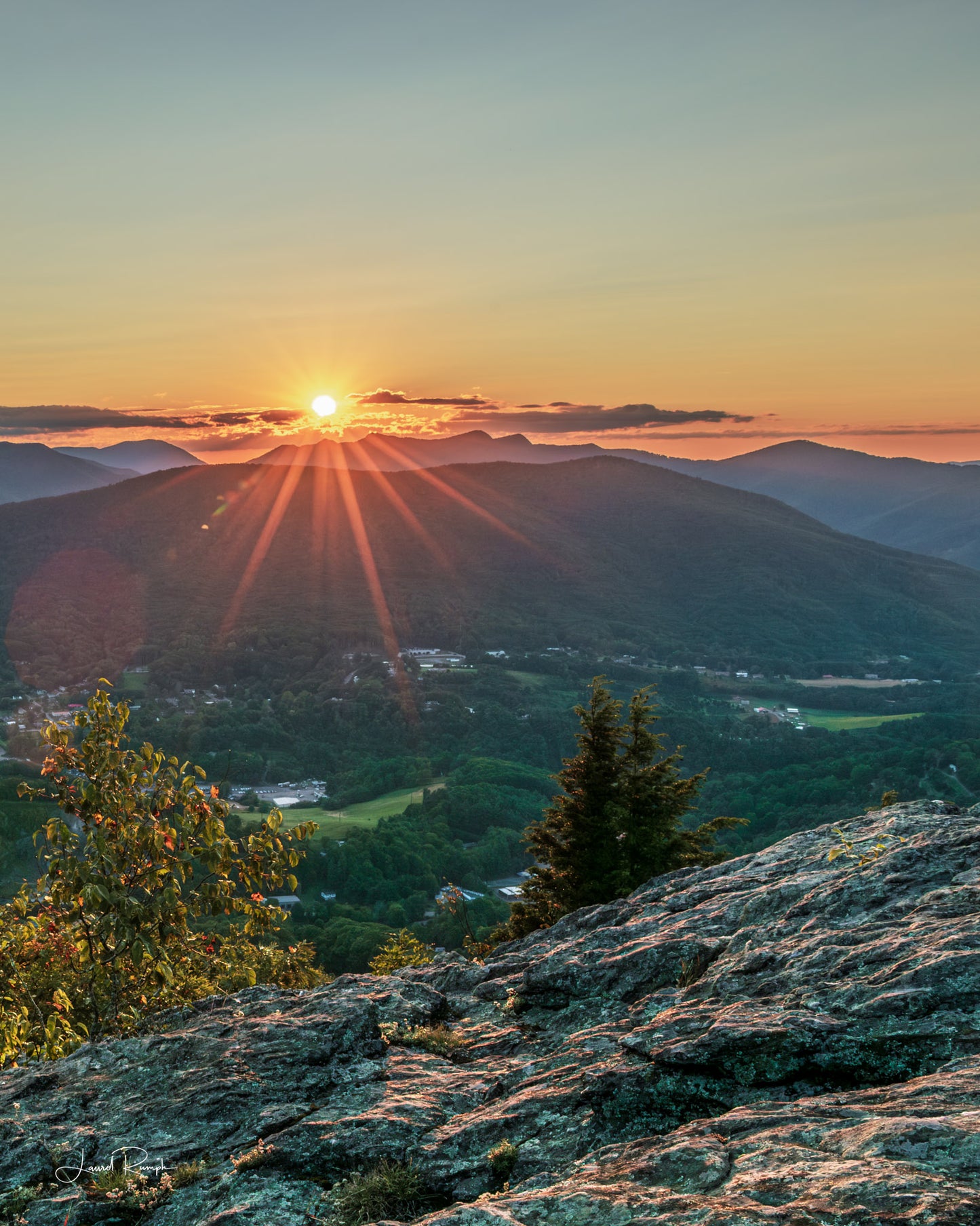 Sunset view from Jefferson overlook on top of Mount Jefferson in Ashe County, North Carolina, where the starburst of the sun is peering from behind three top mountain. 4x5 crop
