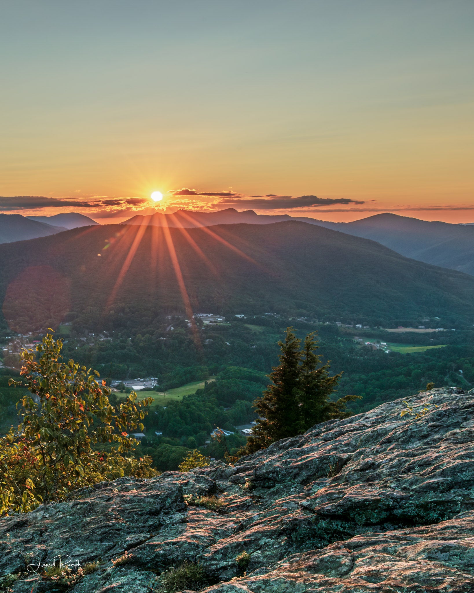 Sunset view from Jefferson overlook on top of Mount Jefferson in Ashe County, North Carolina, where the starburst of the sun is peering from behind three top mountain. 4x5 crop
