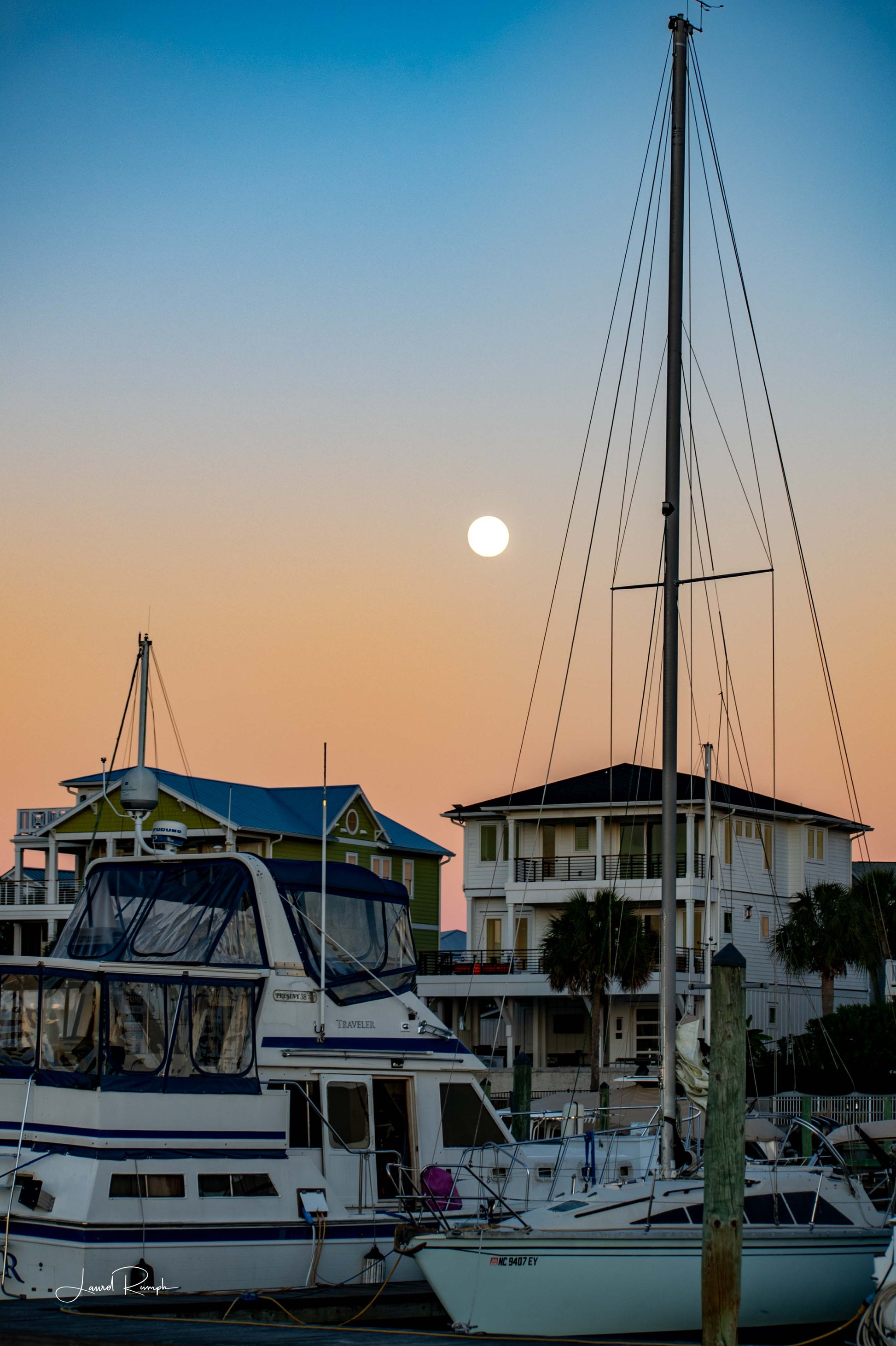 Large sailboats docked at Snow’s Cut Marina in Carolina Beach, North Carolina with a full moon rising behind their masts.