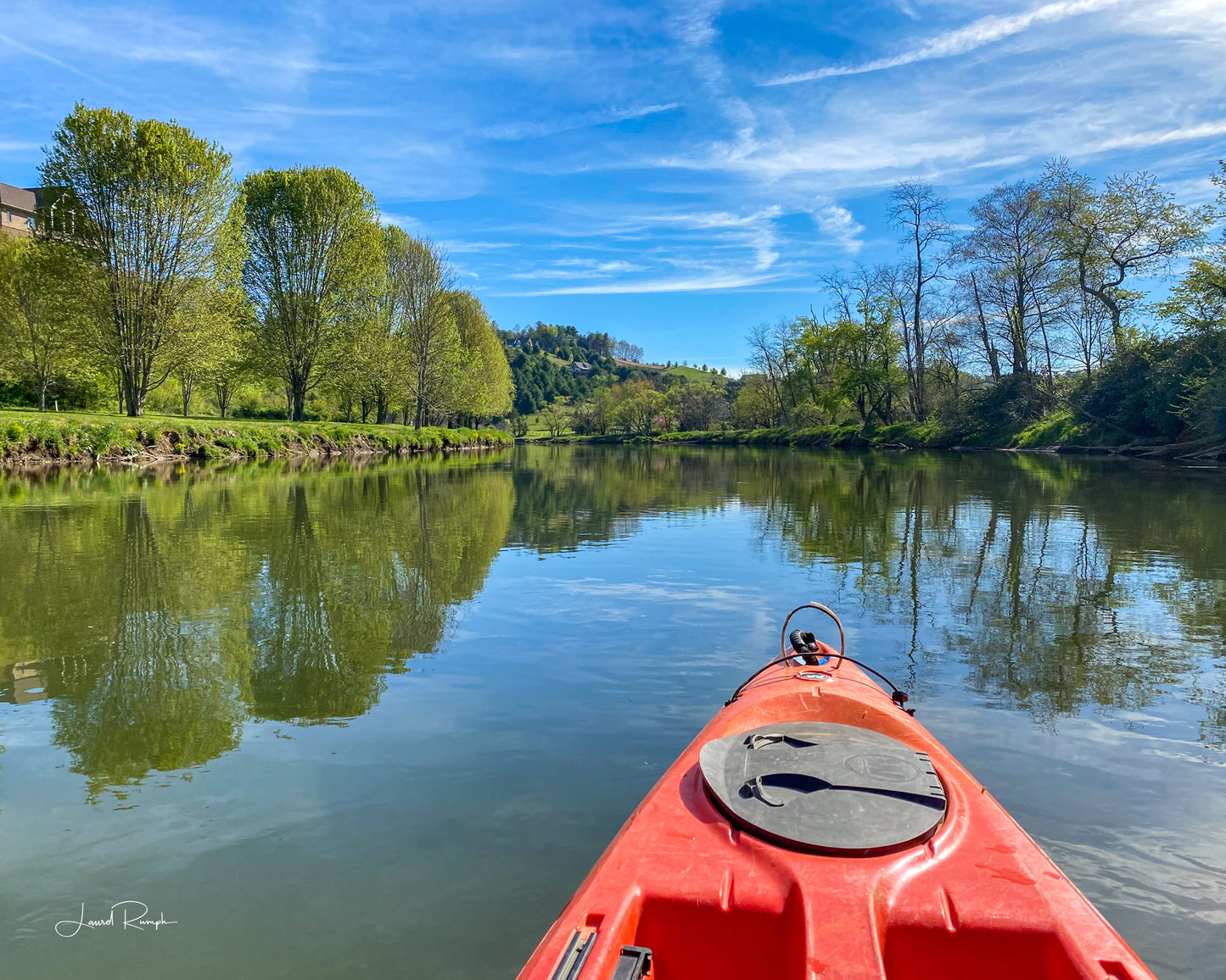 View from a kayak on the New River and a smooth river reflecting beautiful trees and skies in Ashe County, North Carolina.